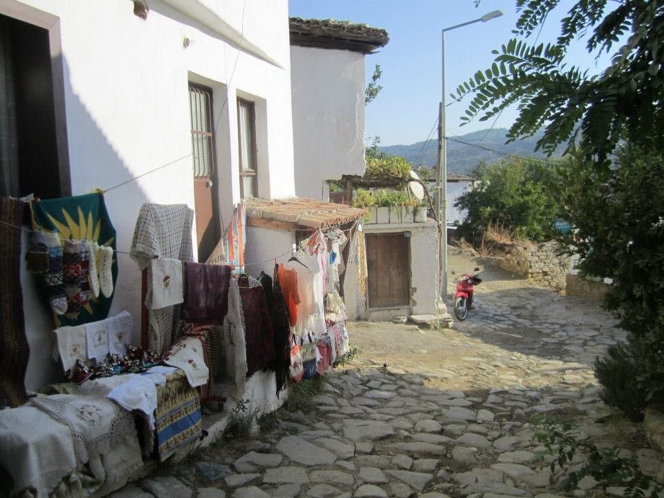Textiles and rugs displayed along a narrow stone village street
