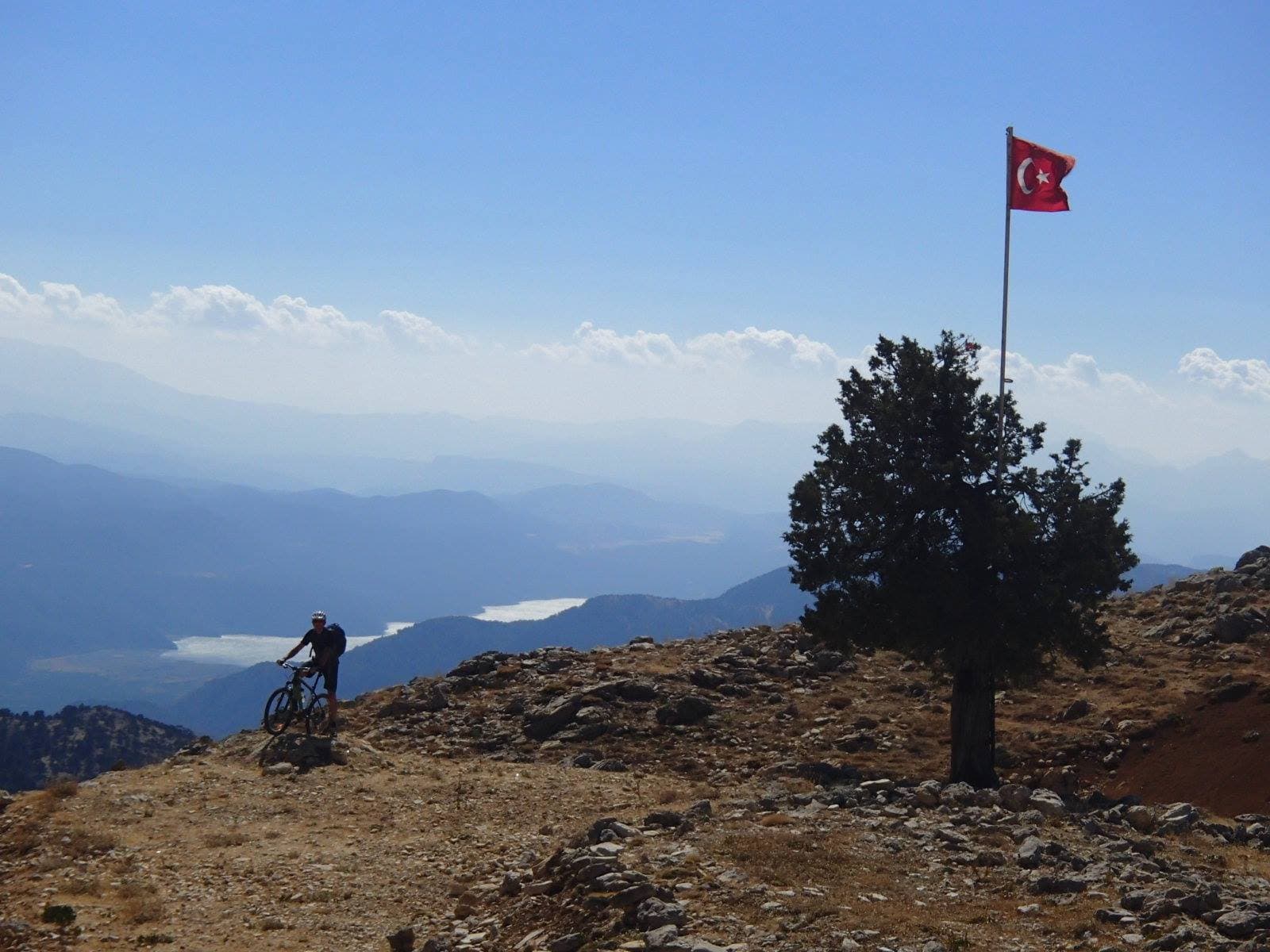 Turkish flag and lone tree marking a summit above a hazy valley in the Taurus Mountains