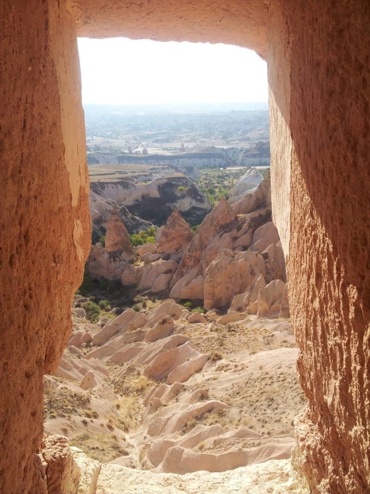 View through a carved rock window framing a valley of fairy chimneys