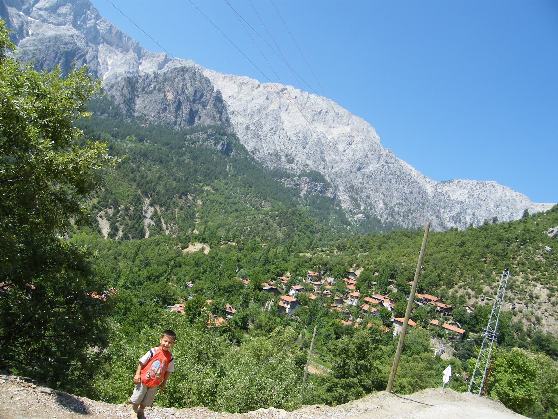 Village rooftops in a green valley below a rocky peak in the Taurus Mountains