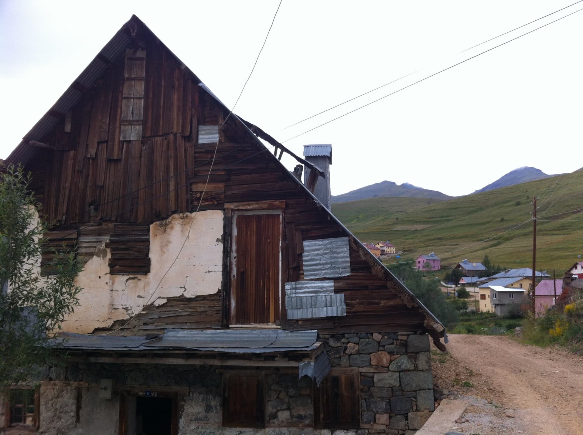Weathered wooden and stone barn beside a dirt road in the Kackar Mountains