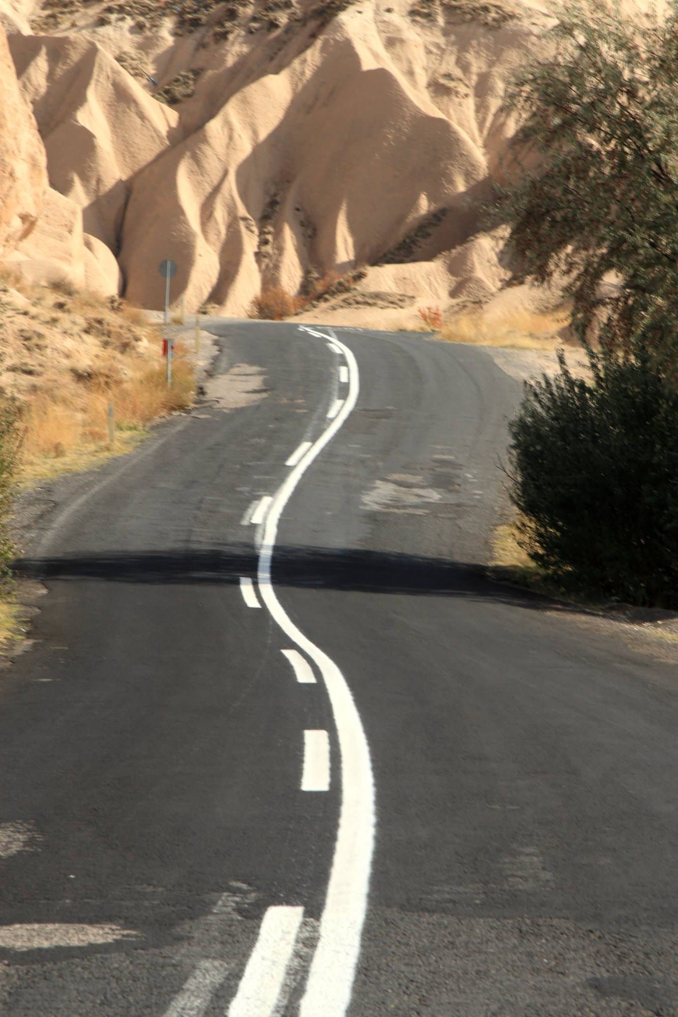 Winding asphalt road curving between soft tuff cliffs in Cappadocia