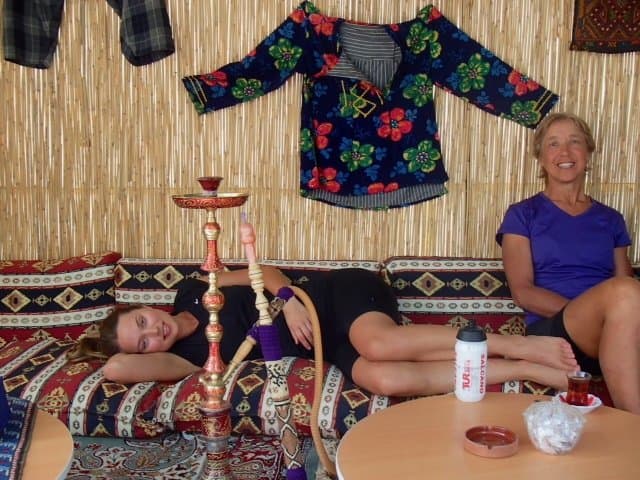 Woman relaxing on cushions beside a hookah in a traditional Turkish tea house