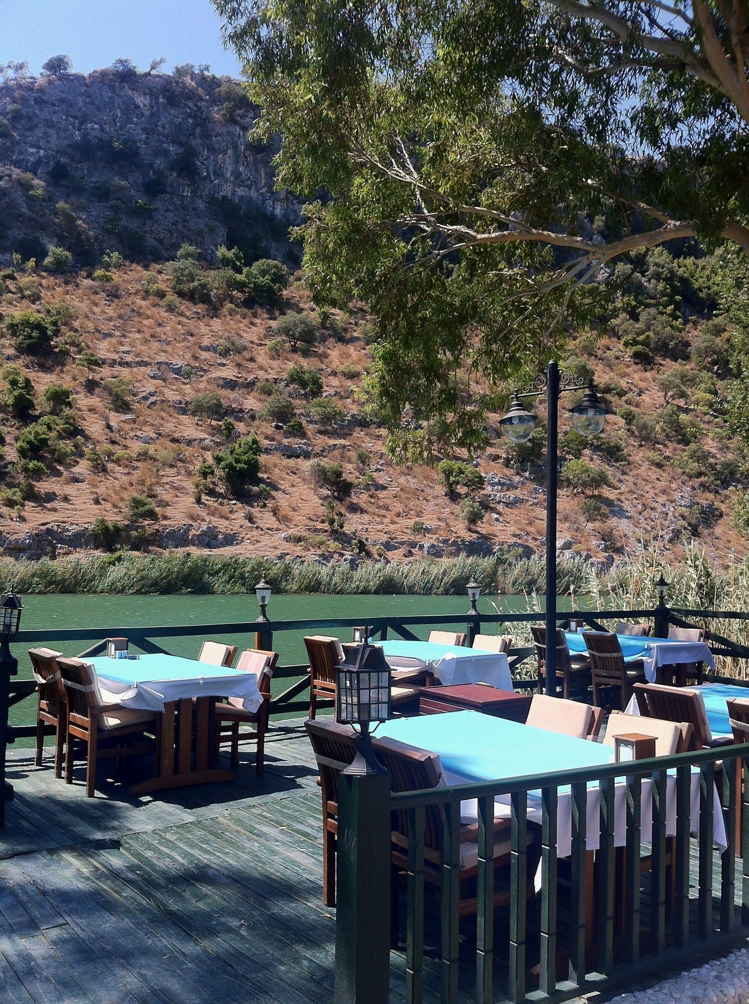 Wooden deck restaurant with blue-topped tables overlooking the water